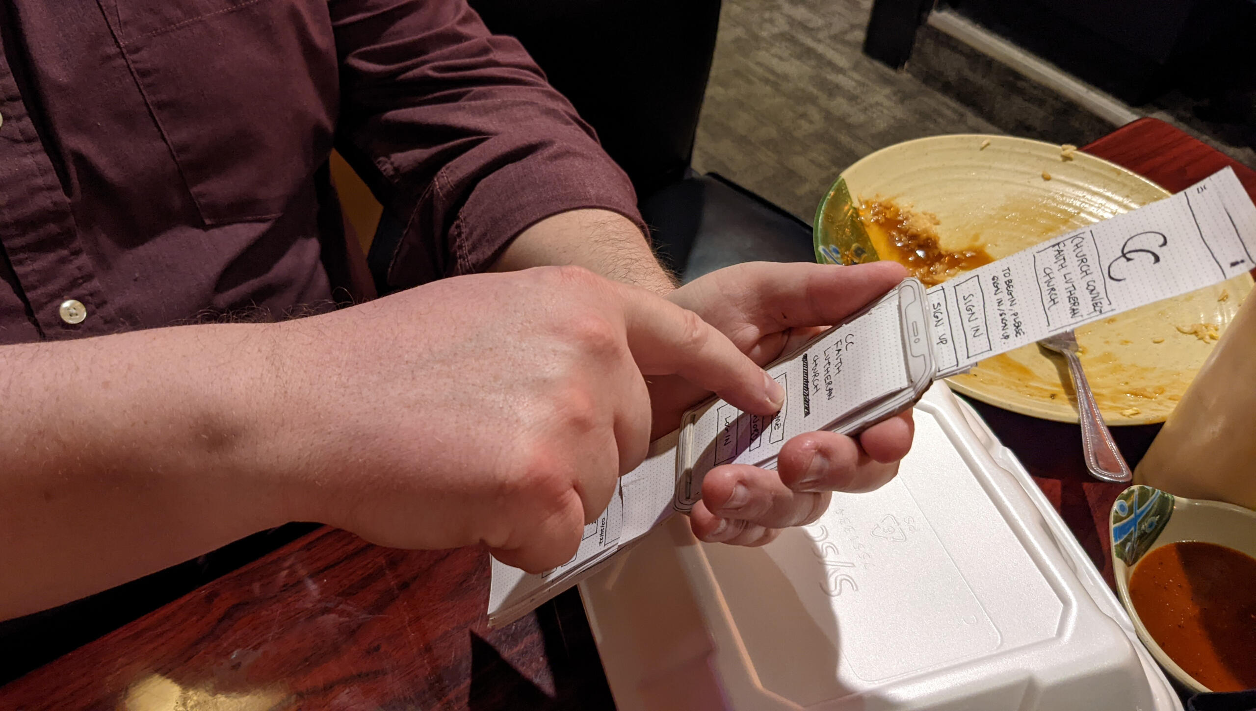 User 1 testing the paper prototype of &quot;ChurchConnect&quot; over dinner.